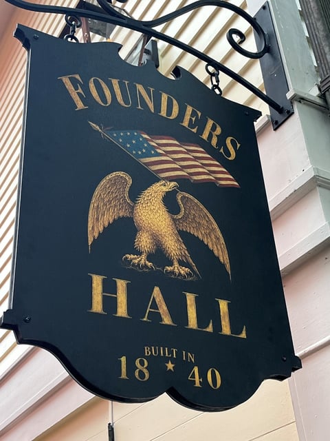 Hanging sign with a gold eagle and flag design for Founders Hall, printed to look hand-painted