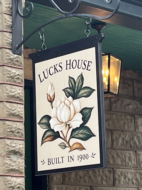 Cream hanging sign with a magnolia illustration for Lucks House, made with wide format printing to look hand-painted